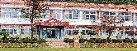 현관 위에 «창작스튜디오» 간판이 걸린 옛 학교 2층 건물